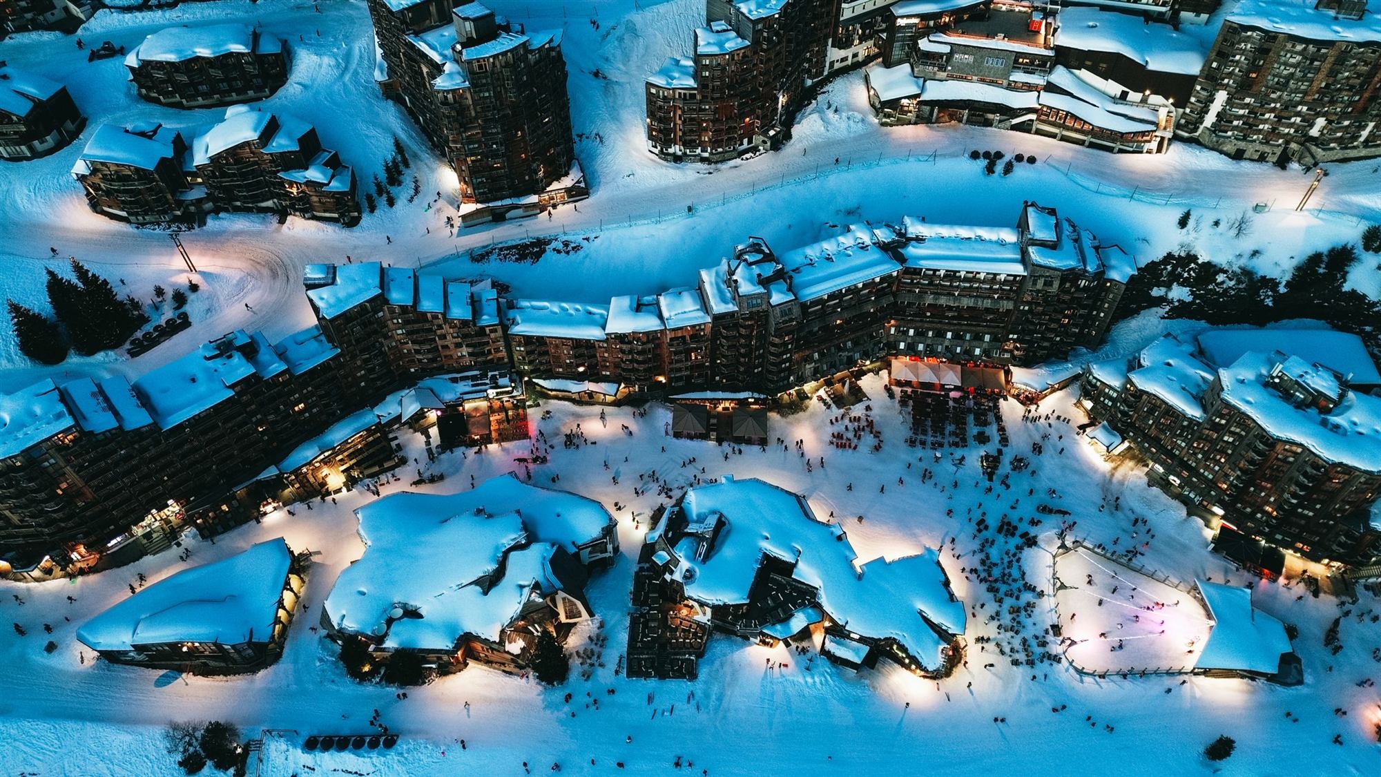 Vue aérienne d'Avoriaz de nuit, résidences enneigées et front de neige éclairé